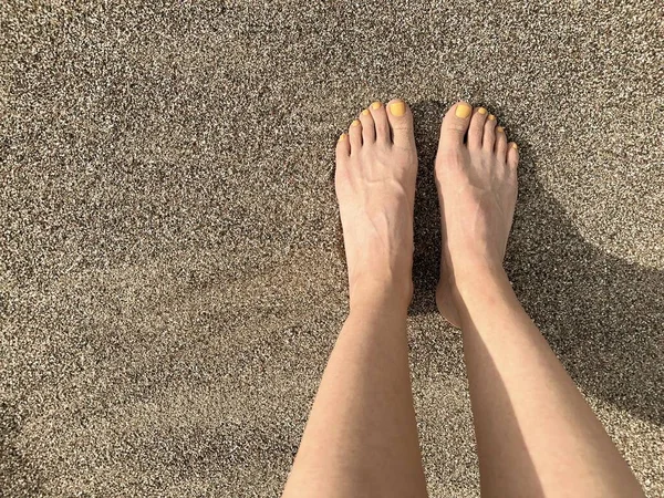 这个女孩在金色的日落中把脚放在沙滩上 她脚趾上的黄色指甲油 顶部视图 为您的文字腾出的空间 — 图库照片