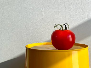 Beyaz arka planda bir domates ve parlak sarı detaylarla dolu bir hayat.