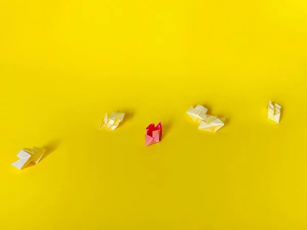 stock image Group of white paper ships and one pink paper boat on a yellow background. Teamwork and leadership concept. Origami