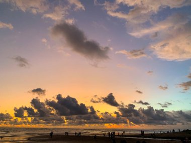 Denizin üzerinde güzel dramatik günbatımı gökyüzü. Kıyıdaki insanların siluetleri