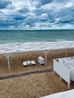 Fırtınalı deniz ve dramatik gökyüzünün arka planında düşük bir turizm sezonunda sahil denizi 