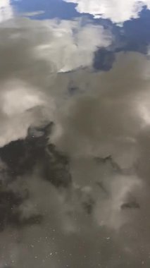 Mavi parlak gökyüzünün yansıması ve sakin sulardaki bulutlar