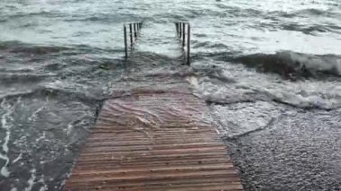 Denize giden ahşap yol taşmış. Gelgit, fırtına, su seviyesi yükseldi. Bulutlu gün, aktif dalgalar