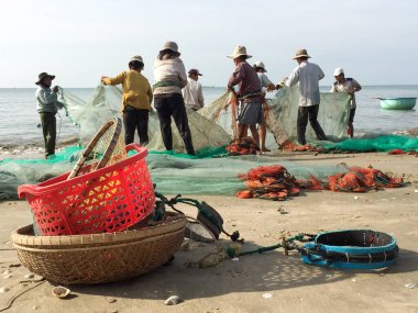 Phan Thiet - 14 Kasım 2015: Balıkçı Limanı. Yerel balıkçılar kıyıya balıkçı ağları dökerler. Önde sepetler, kovalar ve diğer balıkçı aksesuarları var..