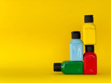 Sarı arka planda parlak renkli akrilik boyalı dört kavanoz. Yeşil, mavi, kırmızı, sarı