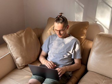 Kafasında komik kuyruğu olan müteahhit programlamaya odaklanmış. Adam gün batımında deri bir koltukta evden çalışıyor, serbest çalışan.