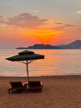 Körfeze bakan iki lüks güneş şezlongu ve dağlarda gün batımı. Ruhu rahatlatmak için ideal bir yer, metin için boş alan