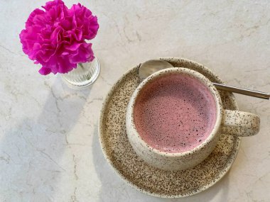 Pembe kremalı ve pembe çiçekli kapuçino bardağı..