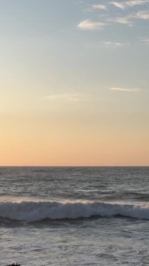 Turuncu ve pembe bir günbatımına karşı denizdeki kusursuz dalgalar.