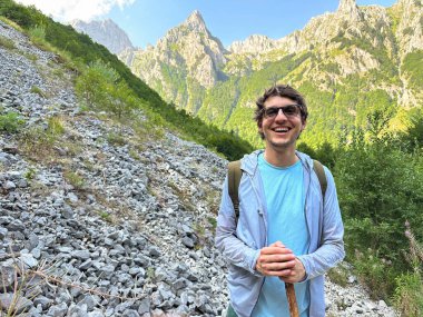 Muhteşem manzaralı kayalık bir dağ yolunda duran gülümseyen yürüyüşçü..