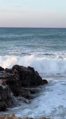 Gün batımında güçlü dalgalar kayalıklara çarpıyor..