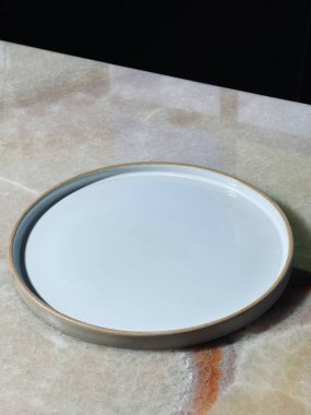 Hafif mermer yüzeyde minimalist beyaz seramik plaka.