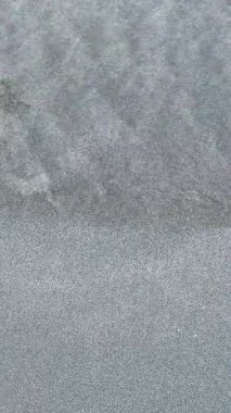 Okyanus dalgaları yumuşak kumlu sahil kıyısında yavaşça akıyor..