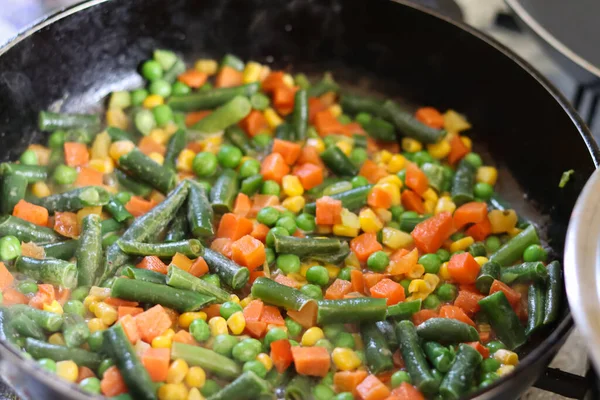 Bright vegetable mix in a frying pan.Frying vegetables in a frying pan.Healthy frozen vegetables. Cooking.Vegetarian food.Assorted vegetables.Mexican mix of vegetables for frying. Table setting.salad.