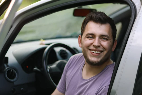 Man driving.First car.Driving school.Renting a car.Happy young man sitting in the auto.Happy moment.Traveling by car.Man smiling.boy with beard.he sits in the car.Brutal man.Ukrainian.Emotion.happy.handsome young man laughing in the car.first car