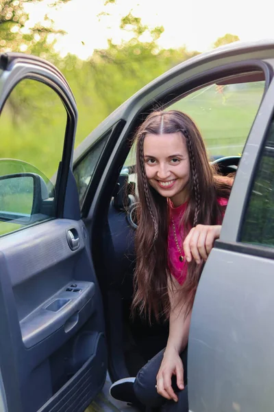 Happy woman is sitting in the car.Woman driving.Rent a auto.car rental.Driving school.Auto enthusiast.Traveling by car.Driver.Auto in nature.Girl sitting in the car.happy emotions.The girl smiles.Beautiful girl with long hair.happy playful woman