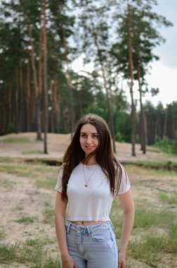 Parktaki bir yaz ormanında bir kız. Ormanda bir kadın. Esmer bir kadının portresi. Doğada bir kızın fotoğrafı. Ormanda güzel bir portre. Ormanda poz veren bir kadının yüksek kaliteli fotoğrafı..