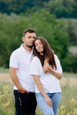 Genç bir çift yaz günü dışarıda kucaklaşır. Bir yaz parkında kucaklaşır. Romantik bir randevu. Sevgililer Günü. İki insanın aşkı. Gerçek bir çift.