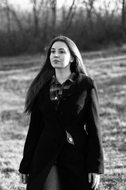 Kadın yana bakıyor. Ciddi duygular. Güzel, uzun saçlı bir kadın. Paltolu bir kadın. Klasik bir fotoğraf. Siyah ceketli güzel bir kız.