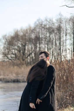 Siyah elbiseli kadın ve erkek sarılıyor. Aşk hikayesi. Bir erkekle bir kadın arasında aşk hikayesi. Göl kenarında fotoğraf. Mutlu karı-koca..
