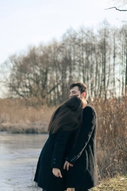 Siyah elbiseli kadın ve erkek sarılıyor. Aşk hikayesi. Bir erkekle bir kadın arasında aşk hikayesi. Göl kenarında fotoğraf. Mutlu karı-koca..
