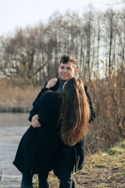 Siyah elbiseli kadın ve erkek sarılıyor. Aşk hikayesi. Bir erkekle bir kadın arasında aşk hikayesi. Göl kenarında fotoğraf. Mutlu karı-koca..