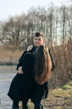 Siyah elbiseli kadın ve erkek sarılıyor. Aşk hikayesi. Bir erkekle bir kadın arasında aşk hikayesi. Göl kenarında fotoğraf. Mutlu karı-koca..
