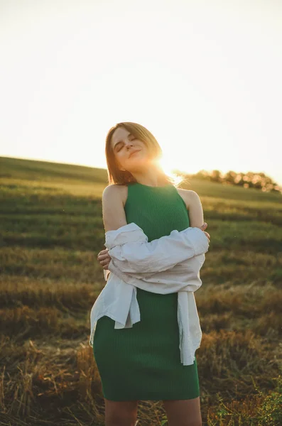 beautiful woman in a dress on the field.Photo of a girl in a field at sunset.Atmospheric photo in a field in sunlight.with short hair.sensual photo of a girl.delicate portrait.sunset portrait.playful woman.Ukrainian.warm retro.vintage.girl dreams.