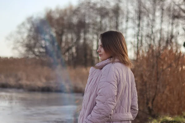 배경에 코트를 아름다운 소녀의 아름다운 여자가 전경에 호수를 바라본다 아름다운 — 스톡 사진