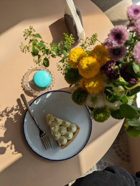 Bir kafede kek. Samimi bir kafedeki bir masanın üzerindeki güzel bir cheesecake 'in estetik fotoğrafı. Makaronlar. Sıcak bir restoran. Masada çiçekler. Tatlılara sevgiler..