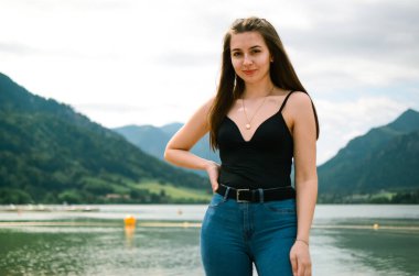 Dağlarda poz veren genç, güzel bir kadın. Bavyera Schliersee 'deki Alplerde tatilde olan genç bir kadın. Yazıt için bir yer. Güzel manzara. Göl kenarında poz veren bir kız.