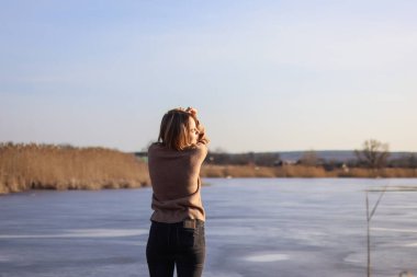 Kazaklı bir kız. Piercingde bir kadın. Suyun yanında yalnız bir kadın. Sakin ve yalnız bir kadın. Rüzgarlı hava. Kendine sarılıyor. Lake. dalgın kadın. Oyunbaz kız.