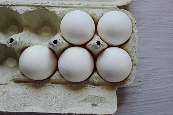 Yuvada tavuk yumurtası, yakın plan, yatay oryantasyon. Yumurtalı karton kutu. Beyaz tavuk yumurtası. Ev yapımı. Mutfakta yemek pişirme. Hobi olarak yumurta pişirme..