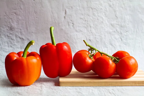 Tahta kesim tahtasında taze kırmızı biberler. Domatesler ve tatlı biberler. Hala sebze satışı. Sağlıklı sebzeler. Vitaminler. Kırmızı sebzeler. Vejetaryenlik..