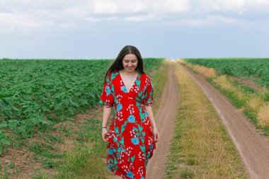 Bir tarlada yürüyen bir kız. Hayatta dengede yürüyor. Tarlada güzel bir kadın. Kendine güvenin ve hayallerinin duyguları. Aşağıya bakan bir kız. Güzel uzun saç.