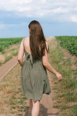 Sahada yürüyen bir kız. Elbise giymiş genç bir kadın yol boyunca yürür. Saç bakımı. Kız arkasında durur. Yalnız bir kadın hayal kurar ve düşünür. Sahada kendini arar.