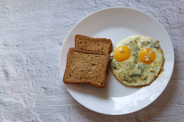 Lezzetli kahvaltı. Sağlıklı yumurta. Mavi peynirli çırpılmış yumurta. Kahvaltı için fikir. Omletli kızarmış ekmek, beyaz bir tabakta. Diyet. Yumurta, sebzenin ilginç bir kombinasyonu.