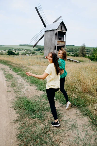 happy couple run in the field near the mill.girlfriends run together across the field.brunette and blonde.Friendship and love.beautiful happy girlfriends.happy sisters.girls are resting in nature.