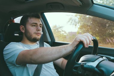 Yakışıklı bir genç adam araba kullanıyor. Kiralık bir araba kullanıyor. Kiralık bir araba kullanıyor. Bir taksi şoförü. Arabadaki kendine güvenen bir adam. Arabayla seyahat ediyor.