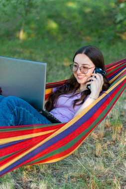 Doğada dizüstü bilgisayarlı bir kadın ile çalışmak. Doğada bilgisayarlı bir kadın. Evden internet üzerinden çalışmak. İnternet üzerinden eğitim. İş kadını. Sohbet ve iletişim. Kız laptopla iletişim kuruyor. Serbest ancer.Telefonlu ve laptoplu kadın. Tatil üzerinde çalışıyor. Evden işe odaklı kız..