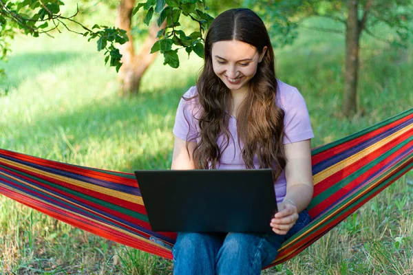 work in nature with laptop.woman with computer in nature.online work from home.online training.business lady.chat and communication.girl communicates with laptop.work from home.freelancer.on a hammock.work on vacation.focused girl.work from home.
