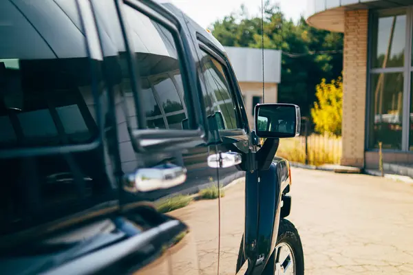 Car side view.Side view mirror.Black vehicle.Beautiful photo of the car.vehicle rear view mirror.The auto stands in nature.Auto mirror.New auto.Auto theme.Automotive.large SUV.car rent.car body.