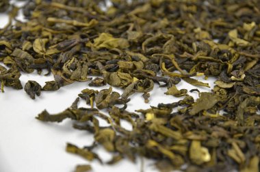 Beyaz zemin üzerinde kuru yeşil yaprak çayı katmanı, yakın plan (makro), kenar görünüm