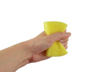 Bir el, izole olmuş bulaşıklar için sarı çamaşır süngeri sıkar.