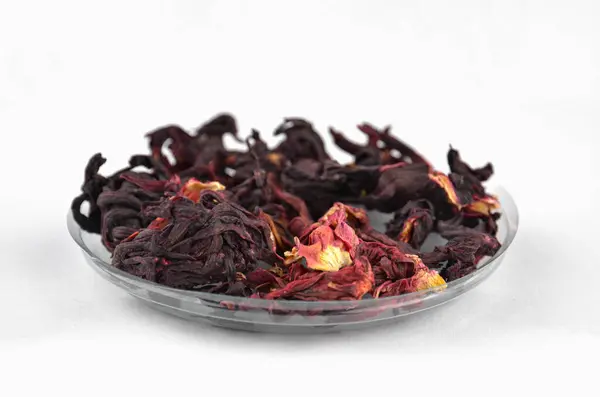 Beyaz zemin üzerinde saydam yuvarlak bir plaka üzerinde, Mısır amblemi kuru kırmızı çay (karkade), yakın plan, makro