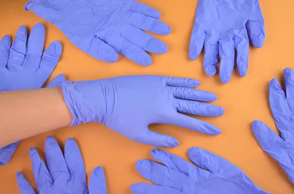 Turuncu arka planda bir grup mavi lateks tıbbi eldiven.