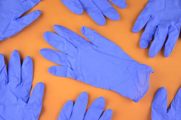 Turuncu arka planda bir grup mavi lateks tıbbi eldiven.