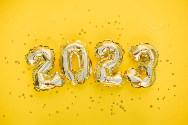 stock image Happy New year and christmas holiday concept 2023. Gold balloons with glitter stars on yellow background. Gift card with space for text. Top horizontal view