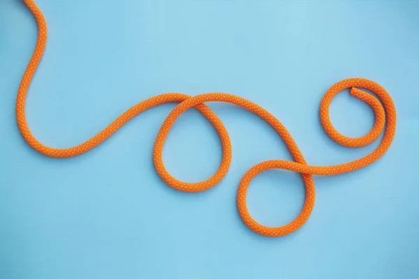 橙色攀爬绳卷曲在蓝色的背景上 免版税图库图片