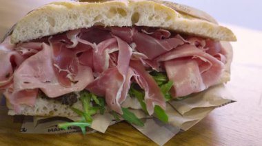 Prosciutto, roket (roket), salsa tartufata (mantar sosu) ve pomodori secchi (güneşte kurutulmuş domates) içeren Focaccia sandviçi.. 